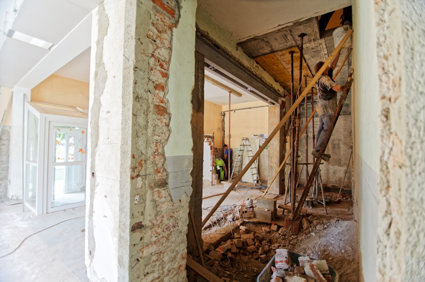 Construction workers renovating a building with exposed brick walls.