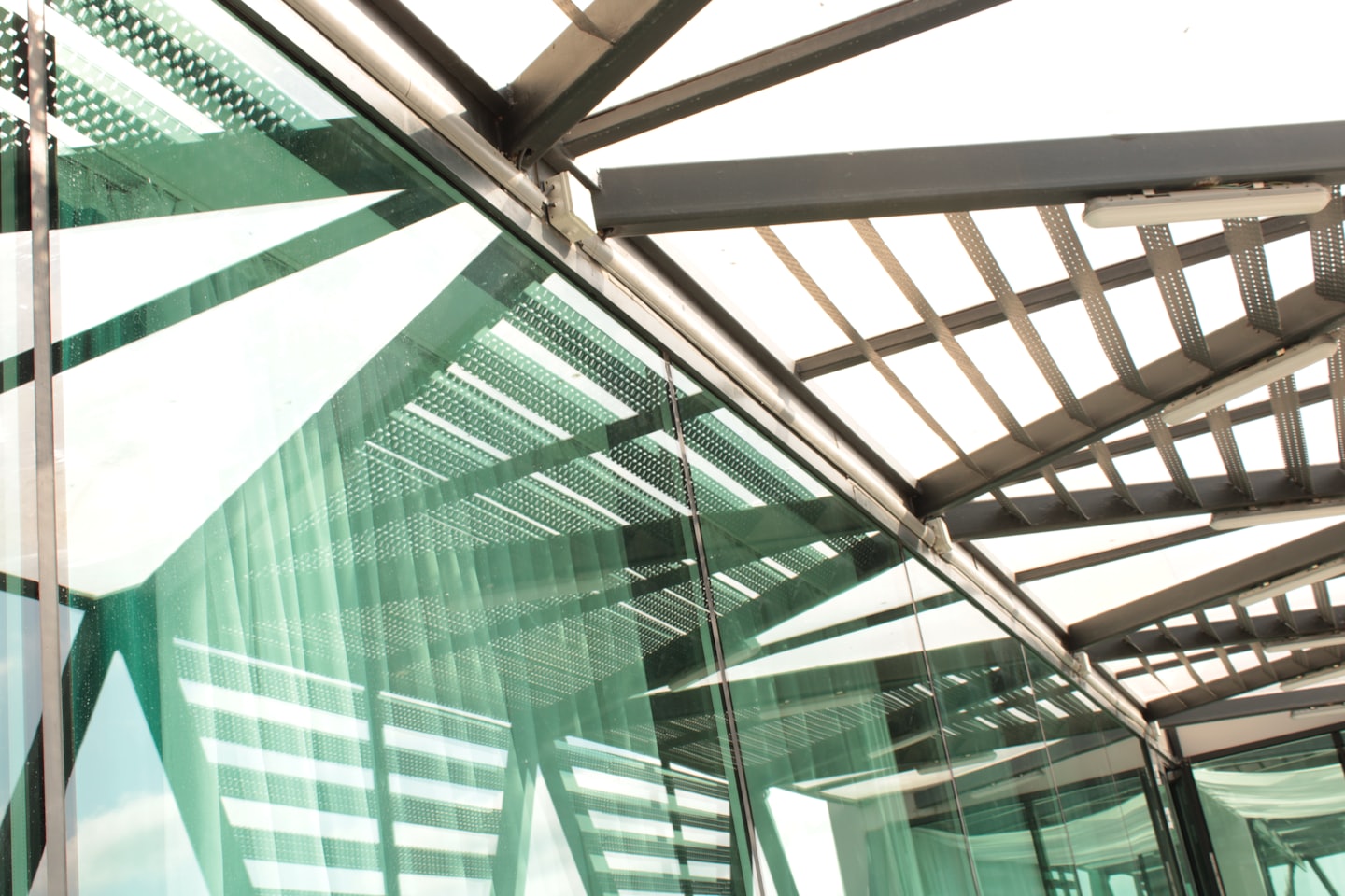 Modern building facade with green glass and dark metal beams.