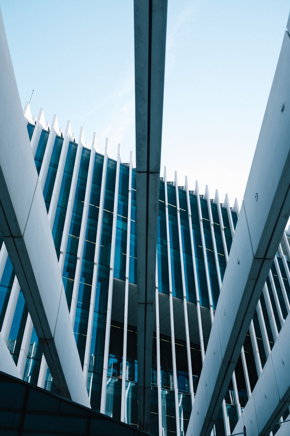 Modern building with blue glass and white fins against blue sky.