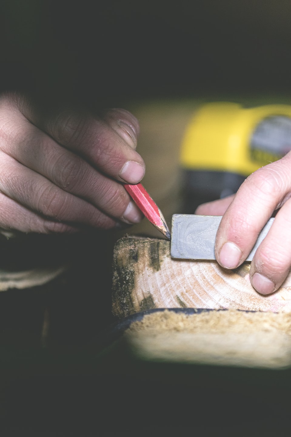 Craftsman's hands mark wood with pencil and ruler.